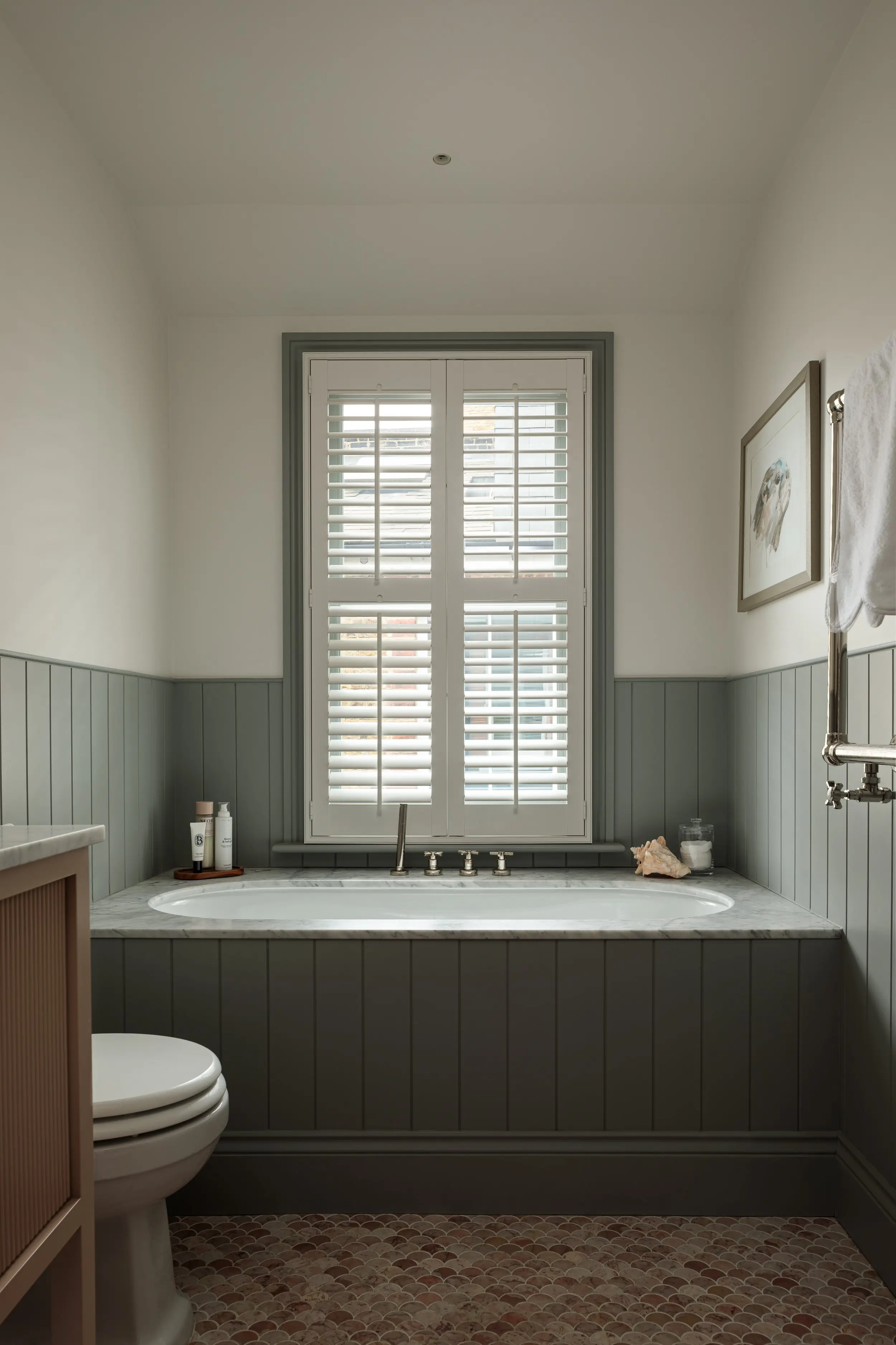 Panelled bath beneath a shuttered window