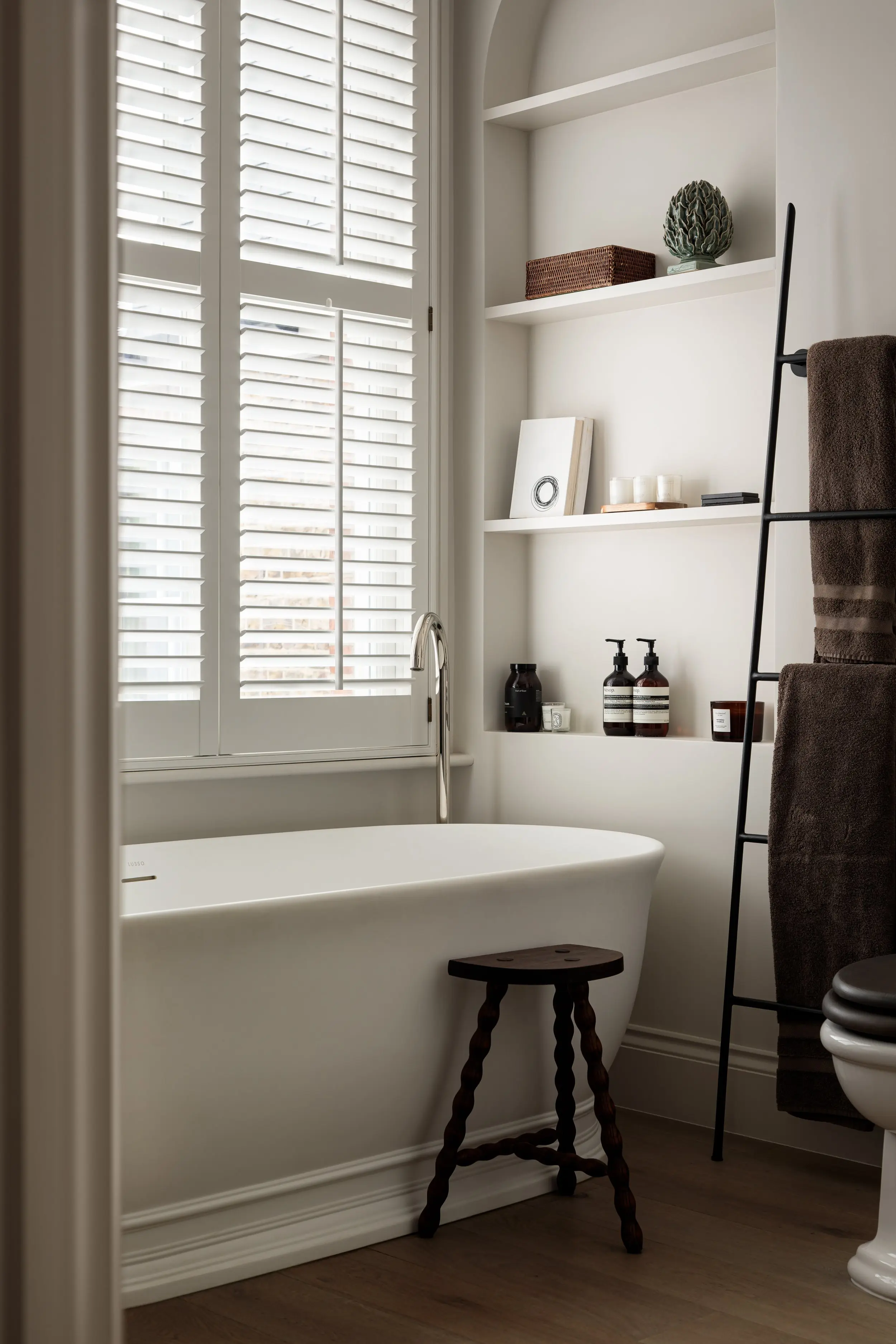 Freestanding bath beside the shuttered window